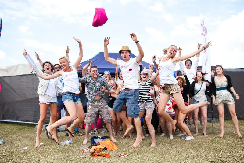 Grupo de jóvenes saltando y celebrando en un festival de música al aire libre